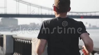 穿着黑色运动服的年轻运动员在城市长廊上奔跑的肖像。 专业运动员在r附近慢跑近景